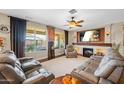 Inviting living room with a fireplace, ceiling fan, plush seating, and large windows offering natural light at 683 W Honey Locust Ave, Queen Creek, AZ 85140