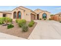 Charming single-story home featuring a tile roof, arched windows, a two-car garage, and professionally landscaped front yard at 25947 W Oraibi Dr, Buckeye, AZ 85396