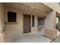 Covered front porch featuring neutral colored walls, a wooden bench and a brown front door at 3022 N Lainey Ln, Buckeye, AZ 85396