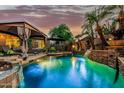 Serene backyard oasis featuring a sparkling pool, stone waterfall feature, and lush landscaping at 3628 E Meadowview Dr, Gilbert, AZ 85298