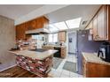 Cozy kitchen with wood cabinets, brick accents, a skylight, and modern appliances at 4323 W Rose Ln, Glendale, AZ 85301