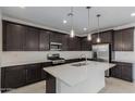 Well-lit kitchen featuring an island with seating, stainless steel appliances, and dark wood cabinetry at 11408 S 50Th Ln, Laveen, AZ 85339