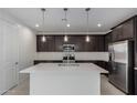 Modern kitchen features stainless steel appliances, espresso cabinetry, a white island, and stylish pendant lighting at 11408 S 50Th Ln, Laveen, AZ 85339