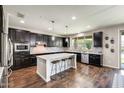 Modern kitchen featuring dark cabinetry, a large island with seating, stainless steel appliances, and hardwood floors at 11875 W Lone Tree Trl, Peoria, AZ 85383