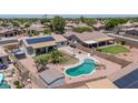 Aerial view of a backyard with a custom pool, lush lawn, and a covered patio area for outdoor enjoyment at 15019 W Banff Ln, Surprise, AZ 85379