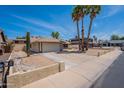 Charming single-story home featuring desert landscaping, a two-car garage, and mature trees accenting the front yard at 7940 W Willow Ave, Peoria, AZ 85381