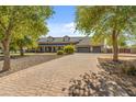 Wide brick driveway leading to a spacious home and three-car garage, framed by mature trees at 1409 E Dove Pl, Casa Grande, AZ 85122