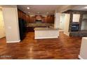 Spacious living room with hardwood floors and a stone fireplace, open to the kitchen at 26449 N 84Th Dr, Peoria, AZ 85383