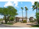 A stunning house with lush greenery, palm trees, a stone chimney, and an arched entryway, showcasing its attractive architecture at 5402 E Cortez Dr, Scottsdale, AZ 85254