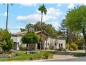 A beautiful single-story home featuring lush landscaping, a stone chimney, and an arched entry for welcoming curb appeal at 5402 E Cortez Dr, Scottsdale, AZ 85254