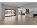 Open floor plan with tile floors, large sliding glass doors to backyard, and modern kitchen at 12332 W Parkway Ln, Avondale, AZ 85323