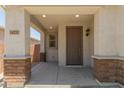Covered front porch featuring stone posts, neutral color palette, and craftsman style door at 14231 W Bronco Trl, Surprise, AZ 85387