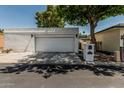 Bright, white stucco home exterior featuring a two car garage with mature landscaping and trees at 225 W Winged Foot Rd, Phoenix, AZ 85023