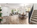 Open-concept living and dining area featuring wood-look tile, white walls, and a modern light fixture at 3875 E Claxton Ave, Gilbert, AZ 85297