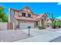 Two-story tan house with a brown roof, two-car garage, desert landscaping, and blue skies at 6928 W Oraibi Dr, Glendale, AZ 85308