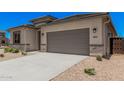Attractive desert-landscaped front yard with a long driveway and a gray two-car garage at 6952 E Brushy Bill Rd, San Tan Valley, AZ 85143