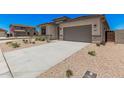 Attractive desert-landscaped front yard with a long driveway and a gray two-car garage at 6952 E Brushy Bill Rd, San Tan Valley, AZ 85143