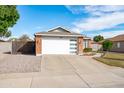 Charming home with a modern garage door, brick accents, and a well-maintained driveway and lawn at 8828 E Des Moines St, Mesa, AZ 85207