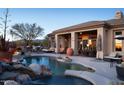 Inviting backyard pool with a rock waterfall feature and plenty of patio seating and desert landscape at 36674 N Vasari Dr, Scottsdale, AZ 85262