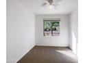 Bright bedroom with neutral carpet, a ceiling fan, and a window overlooking the neighborhood at 42099 W Balsa Dr, Maricopa, AZ 85138