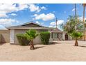 Classic single-story home featuring palm trees and manicured bushes set against a bright blue sky with scattered clouds at 4410 S Grandview Ave, Tempe, AZ 85282