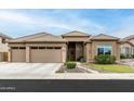 Home exterior showcases a three-car garage, stone accents, and desert landscaping at 6326 W Misty Willow Ln, Glendale, AZ 85310