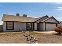 Single-level home featuring an attached two-car garage and low-maintenance desert landscaping at 8703 W Golden Ln, Peoria, AZ 85345