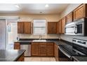 Well-lit kitchen featuring wooden cabinetry, black countertops, and stainless steel appliances at 9 N 87Th N Ln, Tolleson, AZ 85353