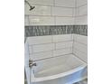 Clean, white, tiled bathtub/shower combination with decorative gray accent tiles and a built in soap niche at 13013 N 18Th St, Phoenix, AZ 85022