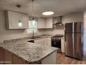 Bright kitchen features stainless steel appliances, granite countertops, and modern pendant lighting at 13013 N 18Th St, Phoenix, AZ 85022