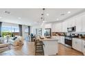 Open-concept kitchen featuring modern appliances, a center island with seating, and seamless flow into the living area at 17479 W Victory St, Goodyear, AZ 85338