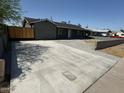 Long, spacious driveway leading to a gray single-story home, accented by a wooden gate at 1915 W Missouri Ave, Phoenix, AZ 85015