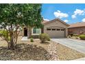 Charming home featuring a two-car garage, a driveway, desert landscaping, and a large tree at 19585 W Washington St, Buckeye, AZ 85326
