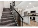 This home features stairs that lead up to a kitchen with stainless steel appliances, white cabinets, and light wood floors at 220 N 22Nd Pl # 1022, Mesa, AZ 85213