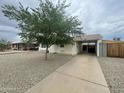 A single-story home boasts a covered parking area, a tree, and minimal landscaping, combining practicality with a touch of nature at 6832 W Vogel Ave, Peoria, AZ 85345