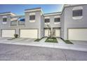 Modern townhouse exterior featuring gray stucco, white trim, individual garages, and tidy landscaping at 1851 W Vermont Ave, Phoenix, AZ 85015