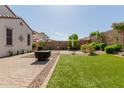 A spacious backyard with a well-manicured lawn, landscaping, brick pavers, and a desert landscaped area in the back at 20556 W Point Ridge Rd, Buckeye, AZ 85396