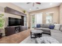 Comfortable living room with a large gray sectional sofa, a ceiling fan, tile flooring and built-in entertainment center at 20556 W Point Ridge Rd, Buckeye, AZ 85396