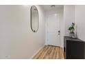 Bright entryway featuring wood-look floors, a modern mirror, and a white front door at 21303 E Estrella Rd, Queen Creek, AZ 85142