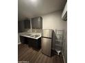 Kitchenette area with stainless steel refrigerator, dark cabinets, and laminate flooring at 4049 N 81St Ave, Phoenix, AZ 85033