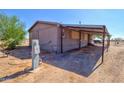 Shows the side of the home with a covered area, utility access, and lots of potential at 43884 W Padilla Rd, Maricopa, AZ 85138