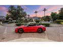 Expansive home exterior with lush landscaping, palm trees, and a red convertible in the foreground at 6611 N 64Th Pl, Paradise Valley, AZ 85253