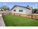 The backyard features well kept artificial turf and a wooden fence at 901 E Hearn Rd, Phoenix, AZ 85022