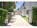 Gated brick driveway showing the side of the Tudor home and an extra building with a white exterior at 921 W Willetta St, Phoenix, AZ 85007