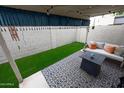 Cozy outdoor patio with white sofa, throw pillows, decorative rug, and small grass area at 16021 N 30Th St # 127, Phoenix, AZ 85032