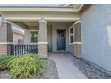 Inviting covered front porch featuring stone accents and a blue front door at 18066 N Stonegate Rd, Maricopa, AZ 85138