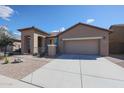 Tan home with large driveway and two-car garage has simple desert landscaping and clay tile roof at 18137 W Deer Creek Rd, Goodyear, AZ 85338