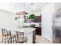 Bright kitchen featuring a center island with seating, dark cabinets, and stainless steel appliances at 36625 W Montserrat St, Maricopa, AZ 85138