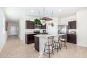 A modern kitchen with dark wood cabinets, stainless appliances, and a granite-topped island with seating at 36625 W Montserrat St, Maricopa, AZ 85138