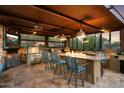 An outdoor kitchen with stainless steel appliances, a brick fireplace, and bar seating at 5630 E Peak View Rd, Cave Creek, AZ 85331